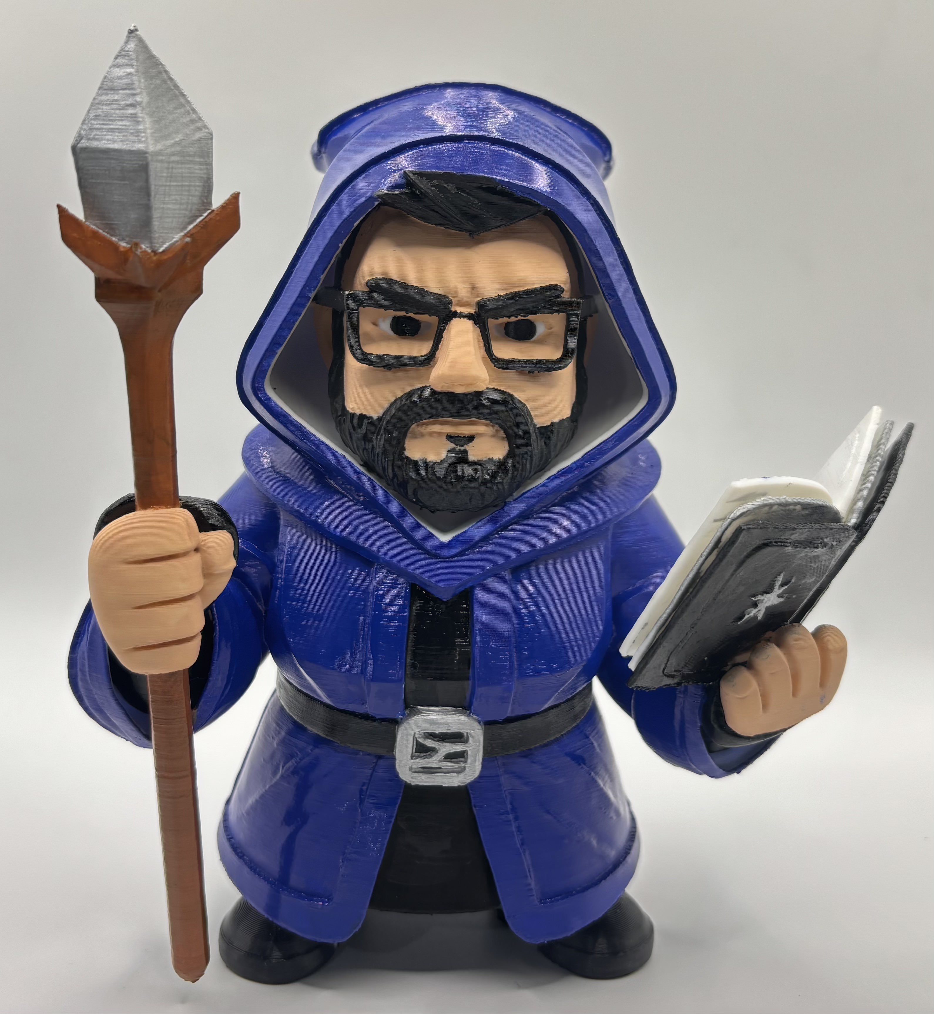Custom 3D printed chibi-style wizard figurine wearing a blue robe, holding a staff and spellbook, hand-painted with detailed facial features.