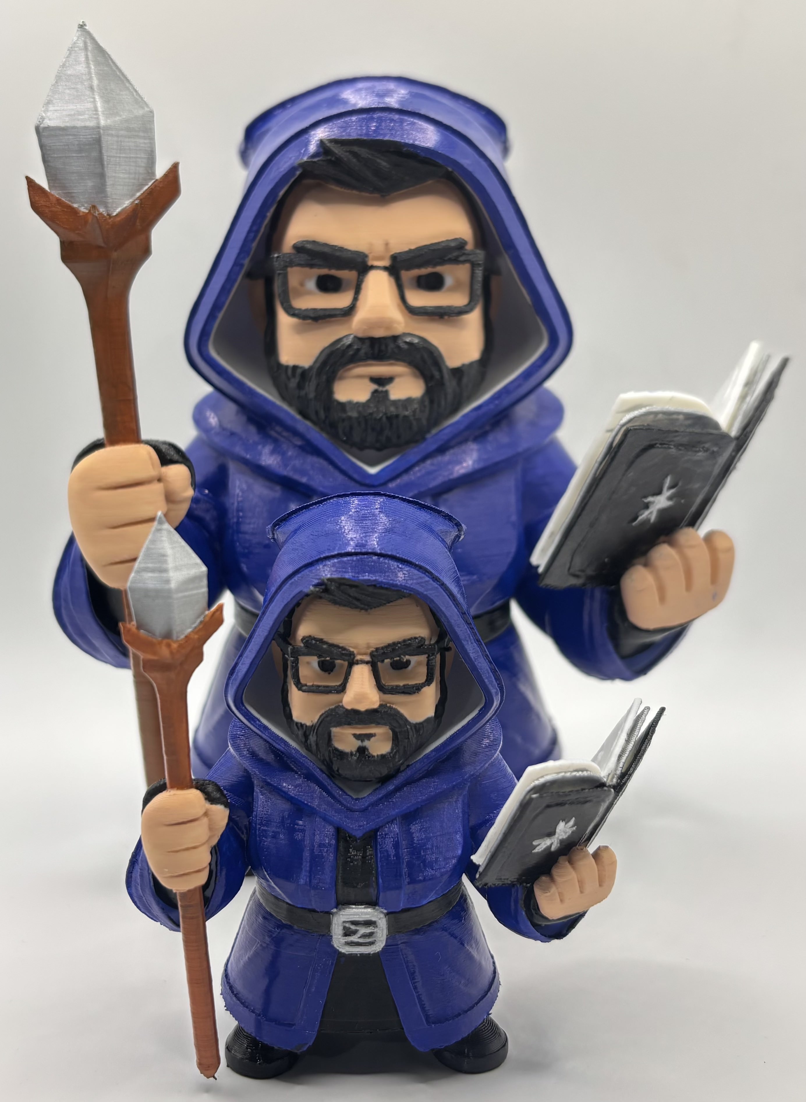 Two custom 3D printed chibi-style wizard figurines in different sizes, featuring blue robes, staff, and spellbook accessories.