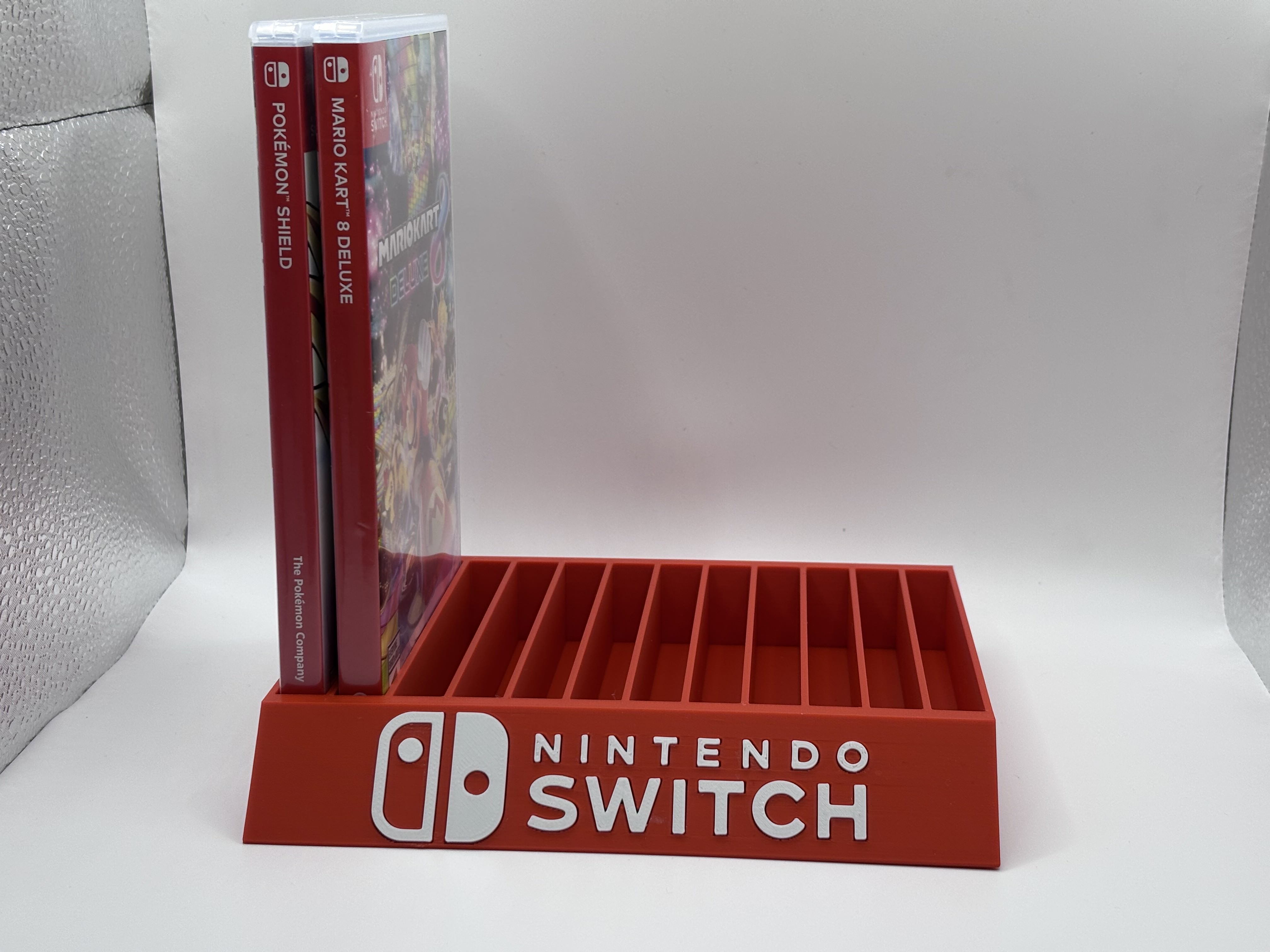 Red 3D printed Nintendo Switch game cartridge holder with multiple slots for organizing physical game cases.