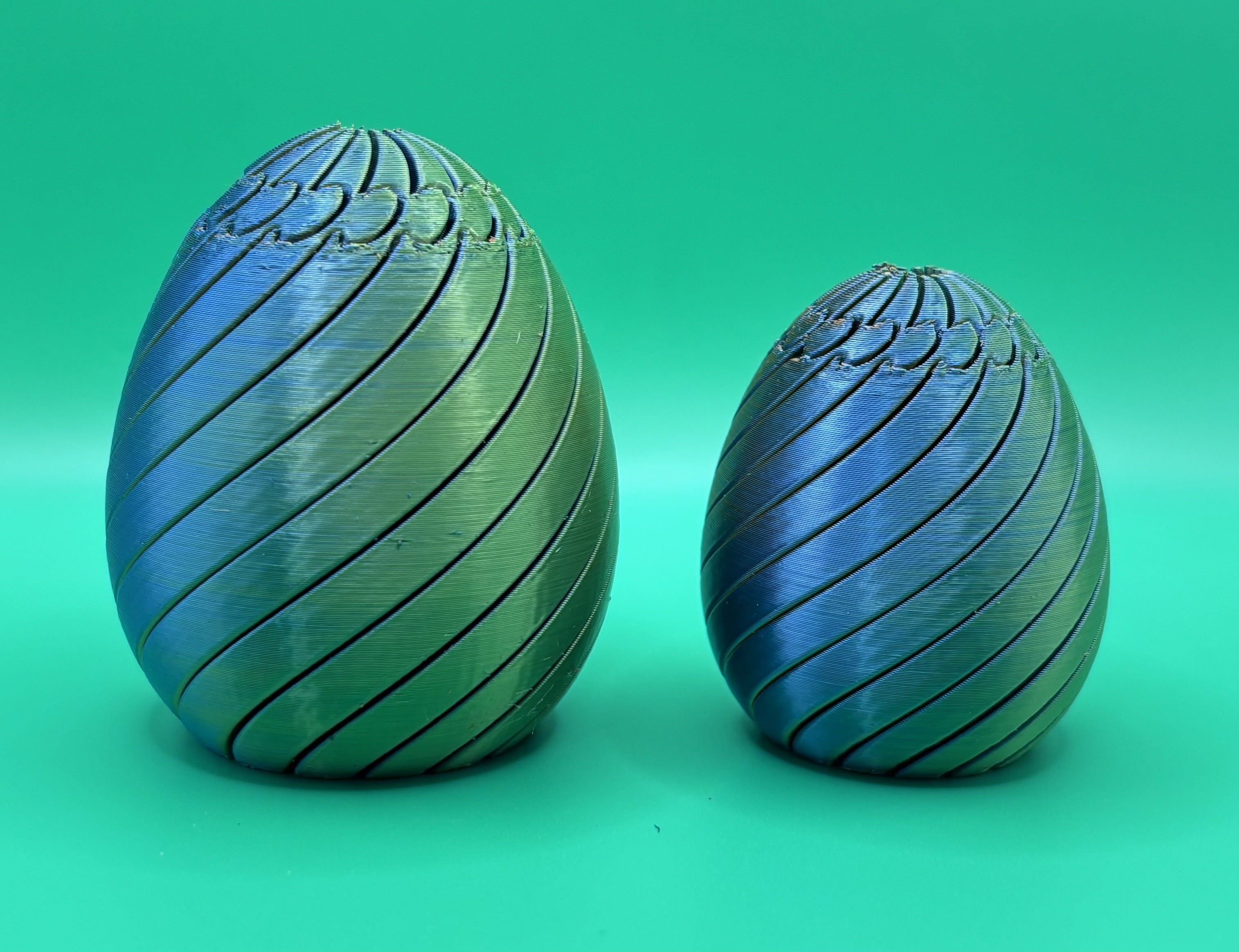 Large and small spiral fidget eggs 3D printed in multicolor filament with segmented twisting design.
