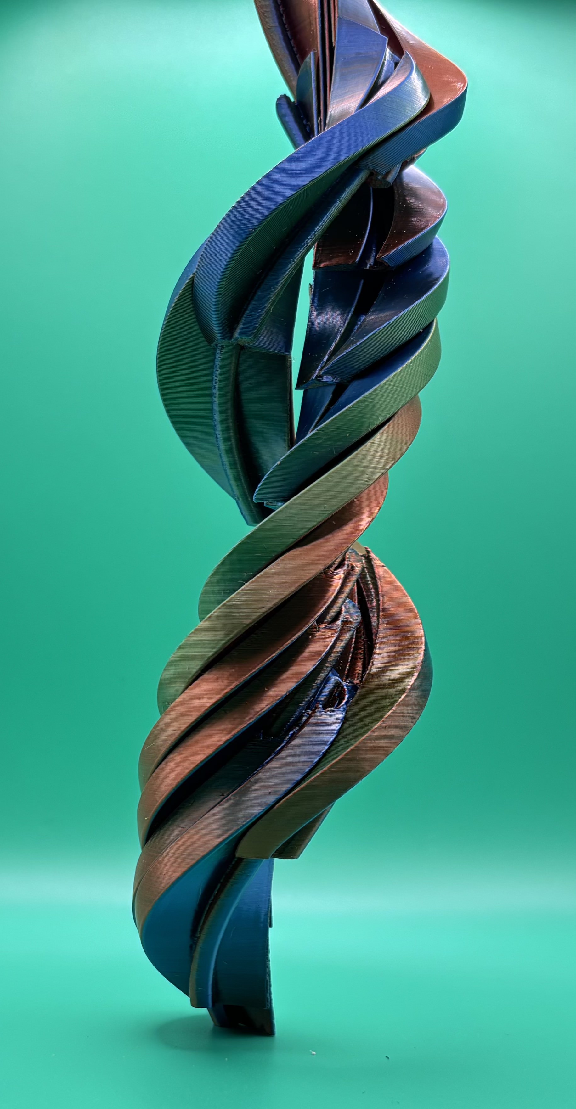 Abstract twisted helix sculpture 3D printed in gradient filament with layered spiral design.