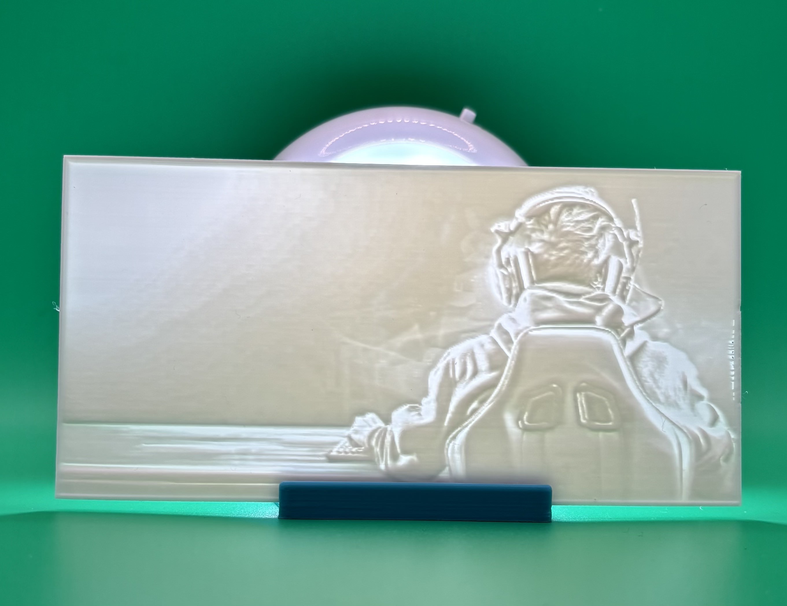 Custom 3D printed lithophane showing a gamer sitting at a desk with headphones, 			keyboard, and gaming chair, backlit personalized photo print