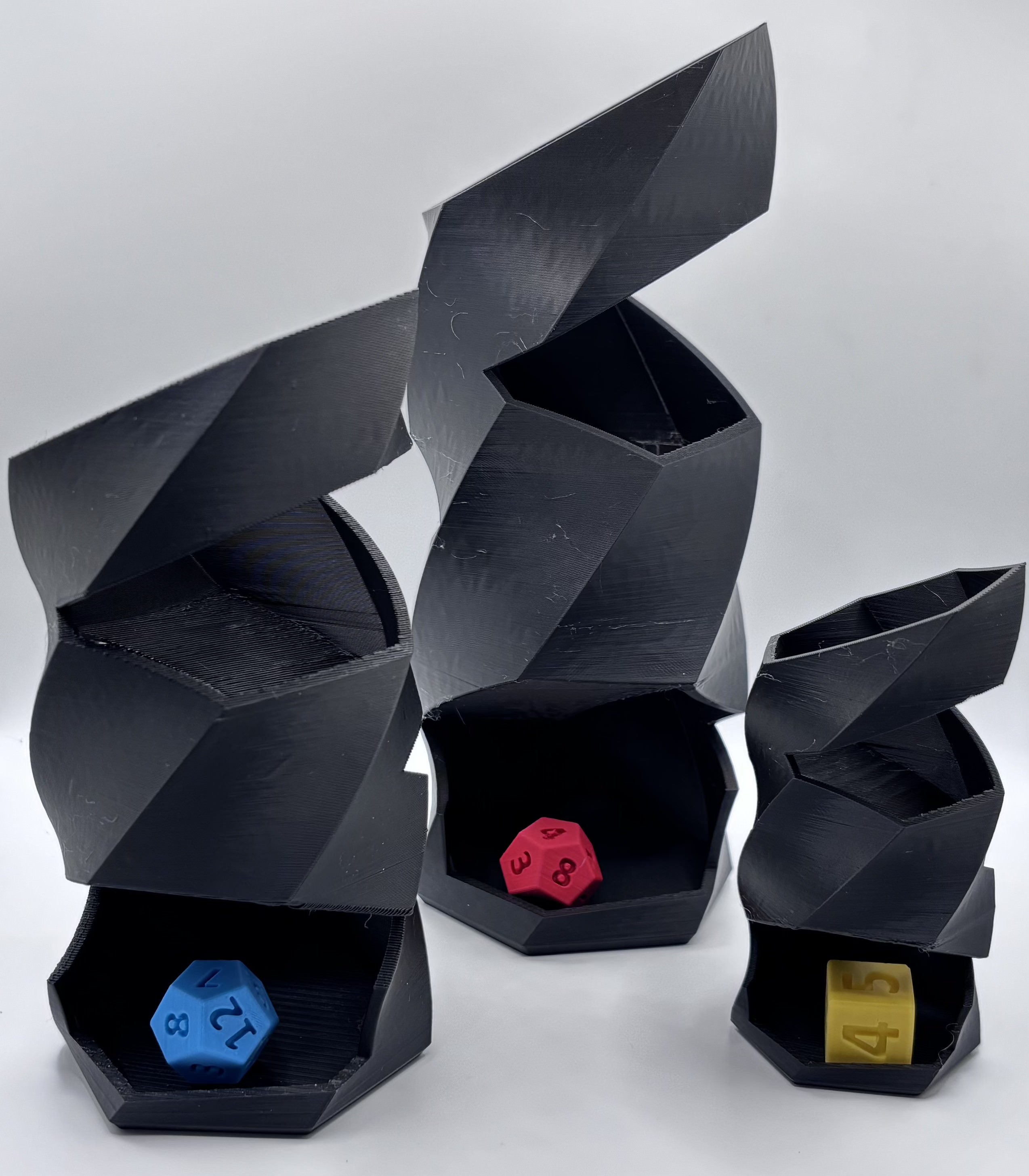 Three sizes of 3D printed twisted dice towers displayed side by side for scale comparison